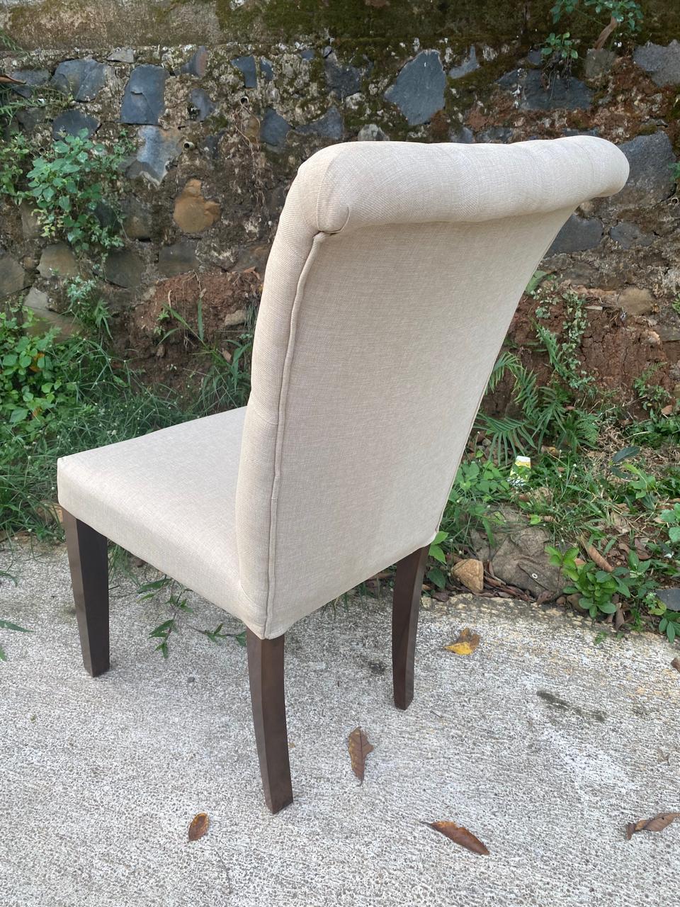 Modern wingless dining chair with plush cream fabric upholstery and teakwood frame