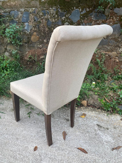 Modern wingless dining chair with plush cream fabric upholstery and teakwood frame